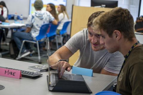 two students working at a laptop